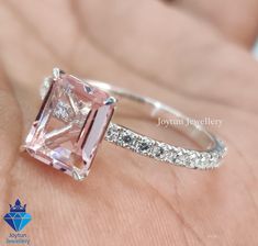 a pink diamond ring on someone's hand with diamonds around it and the words joy written in white gold