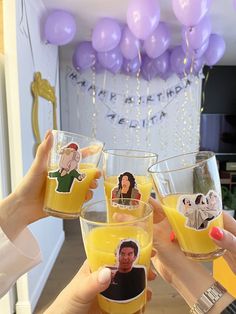 three people holding up glasses filled with orange juice and balloons in the shape of characters