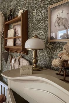 there is a teddy bear sitting on the dresser in this room with wallpaper and pictures