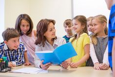 a group of children standing around each other in front of a man holding a blue folder