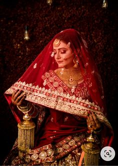 a woman dressed in red and gold is holding a golden lamp with her hand on it