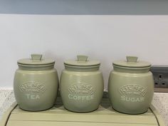 three green canisters sitting on top of a counter