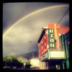 a rainbow in the sky over a building with a theater sign on it's side