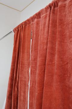 an orange curtain is hanging in front of a white wall with a metal hook on it