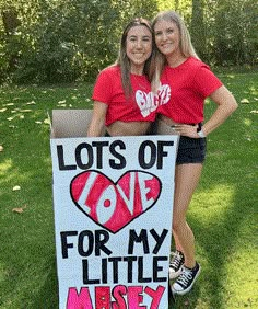 two girls are posing with a sign that says lots of love for my little miss