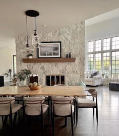 a dining room table with chairs and a fireplace in the backround, surrounded by windows