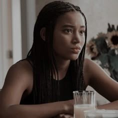 a young woman sitting at a table with a glass of milk in front of her