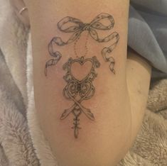 a tattoo on the leg of a woman with scissors and bows around her heart,