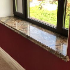 a window sill sitting in the corner of a room next to a red wall