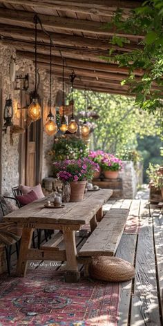 a wooden table sitting on top of a patio next to flowers and potted plants