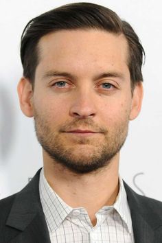 a close up of a person wearing a suit and tie with a beard in front of a white background