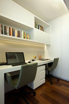 a laptop computer sitting on top of a white desk next to a book shelf filled with books