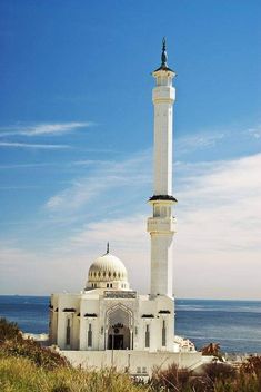 a large white building with a tall tower next to the ocean