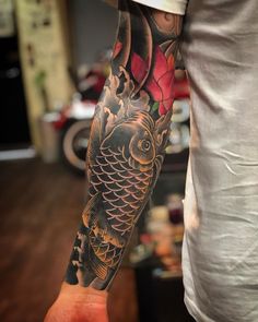 a man with a tattoo on his arm holding a fish and flowers in the water