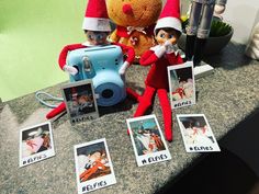 two elfs are sitting on a counter with pictures and a camera