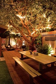 a wooden table under a tree with lights on it