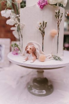 a white cake with flowers and a dog figurine on top