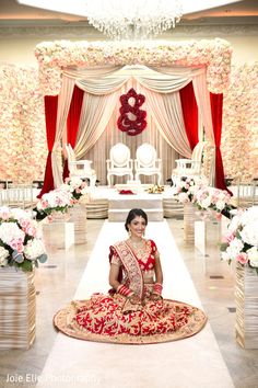 a woman sitting on the ground in front of a wedding ceremony setup with flowers and decorations