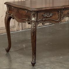 an antique wooden table with ornate carvings on the top and legs, in front of a wall