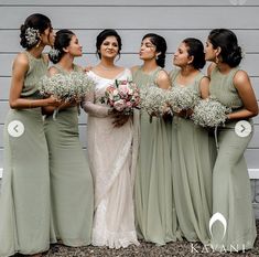 a group of women standing next to each other in front of a gray wall holding bouquets