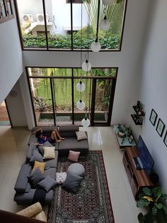 a living room filled with lots of furniture next to a tall glass window on top of a white tiled floor