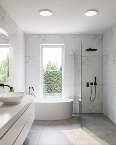 a white bathroom with two sinks and a bathtub in the middle of the room