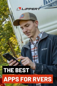 a man is looking at his cell phone while standing in front of a camper