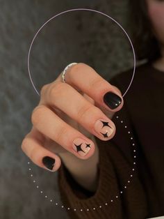 a woman's hand with black and white nail polish holding up a circular object