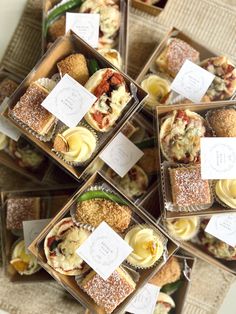 several boxes filled with different types of pastries on top of a cloth covered table