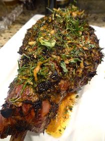 a piece of meat on a white plate covered in herbs and seasoning sitting on a counter