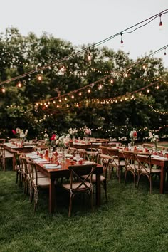 tables and chairs are set up outside for an outdoor wedding reception with string lights strung over them