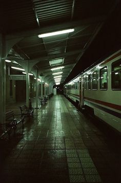 a subway station with benches and lights on the side of the train tracks at night