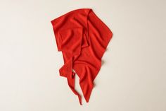 a red scarf laying on top of a white surface