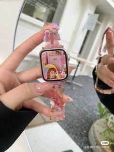 a person holding up a pink watch with pictures on the front and side of it