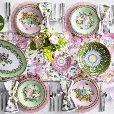 a table set with plates, silverware and flowers in pastel colors is shown from above