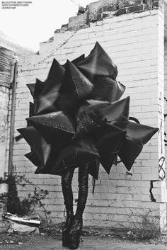 black and white photograph of a woman holding an umbrella in front of a brick wall