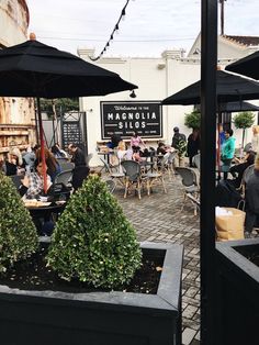 people are sitting at tables with umbrellas over them