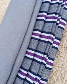 two pieces of fabric laying on the floor next to each other, one with purple and white stripes