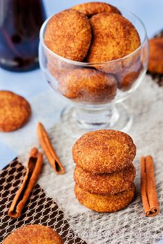 cinnamon sugar cookies stacked on top of each other in a glass bowl next to cinnamon sticks