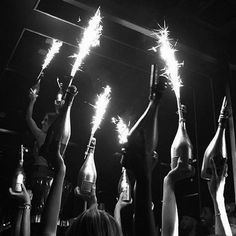 people holding up bottles with sparklers in the air