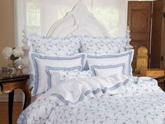 a bed with blue and white comforters in a bedroom next to a table on the floor