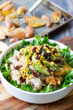 a white bowl filled with chicken and veggies on top of a wooden cutting board