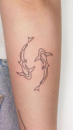 a woman's arm with two dolphins in the shape of a circle on it