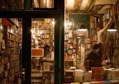 a man standing in front of a bookshelf filled with lots of books at night