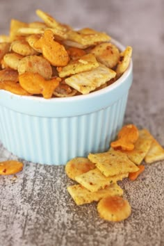 a blue bowl filled with cheetos sitting on top of a counter next to chips