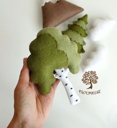 a hand holding a piece of broccoli on top of a white table