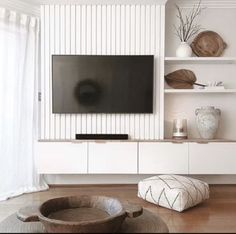 a flat screen tv sitting on top of a white entertainment center in a living room