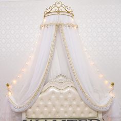 a bed with a white canopy over it and lights on the headboard in front of it