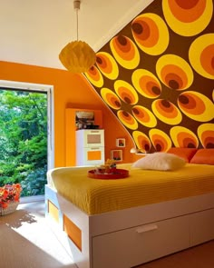 a bedroom with orange and yellow decor on the walls, bed in front of an open window