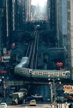 a train is going down the tracks in an urban area with tall buildings and traffic